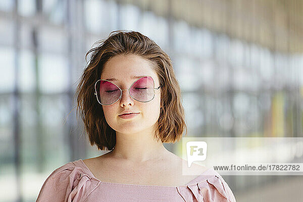 Teenage girl with eyes closed wearing pink sunglasses