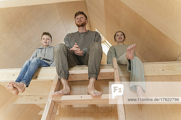 Vater und Kinder sitzen auf der Leiter im zweiten Stock eines Öko-Hauses