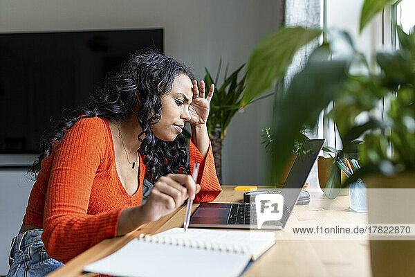 Gestresste Frau konzentriert sich auf die Arbeit mit Laptop im Heimbüro
