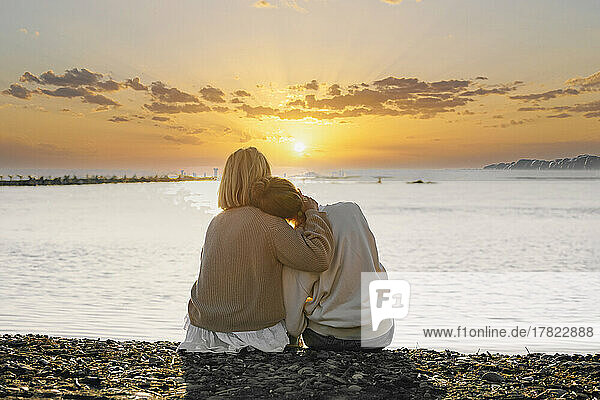 Mutter und Tochter genießen den Sonnenuntergang am Strand
