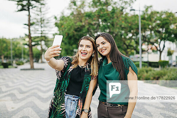Happy friends taking selfie through smart phone in park