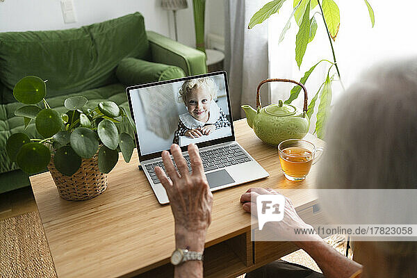 Frau spricht zu Hause per Videoanruf mit Enkelin über Laptop