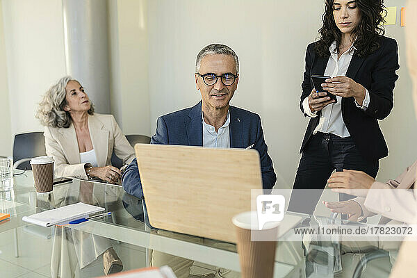 Businessman discussing over laptop in meeting with colleagues at office