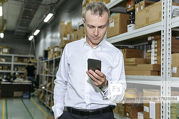 Businessman using smart phone in factory