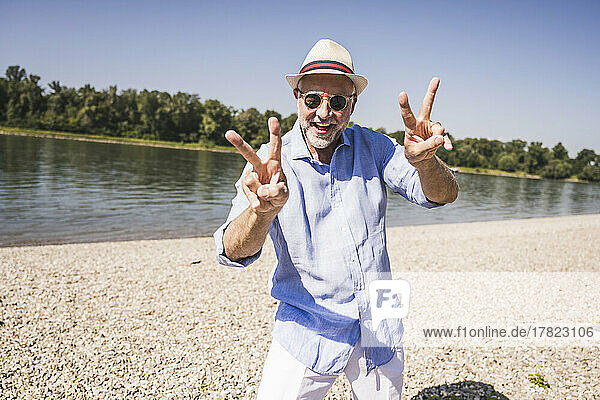 Happy senior man gesturing at riverbank on sunny day