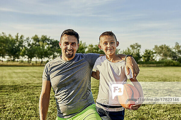 Happy father and son together st sports field on sunny day