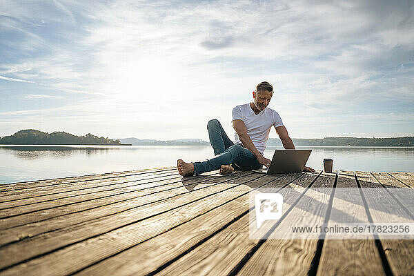 Mature freelancer using laptop on jetty