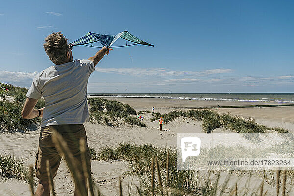 Reifer Mann lässt an einem sonnigen Tag am Strand Drachen steigen