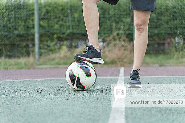 Frau mit Bein auf Fußball im Sportplatz