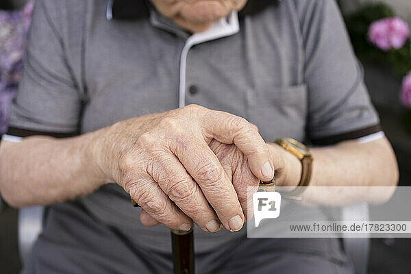 Hands of senior man holding walking cane