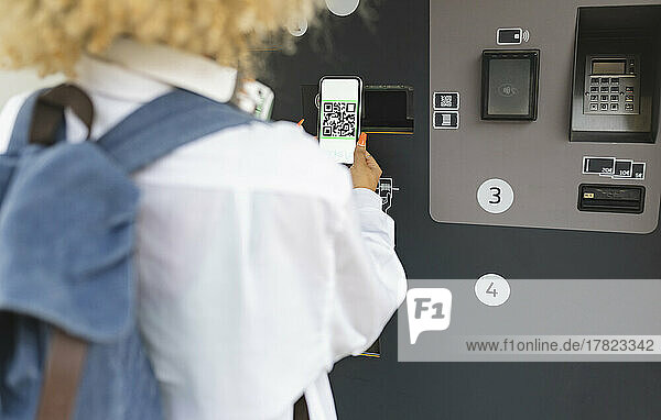 Frau scannt QR-Code am Ticketautomaten
