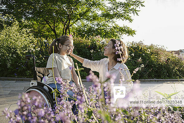 Mother with girl in wheelchair at park on sunny day