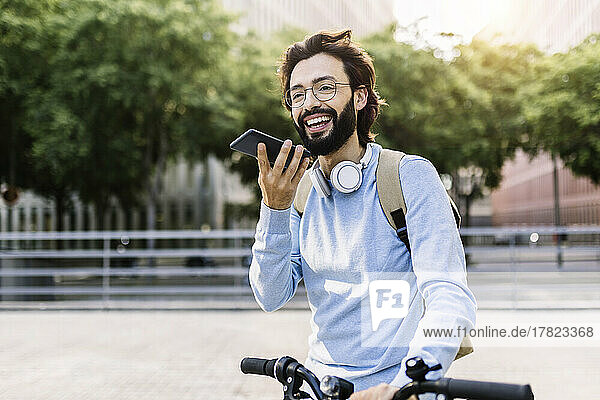 Smiling man wearing wireless headphones talking on speaker phone