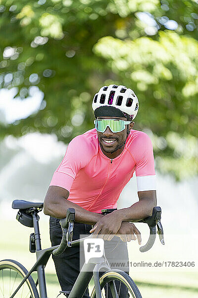 Young cyclist leaning on bicycle in park