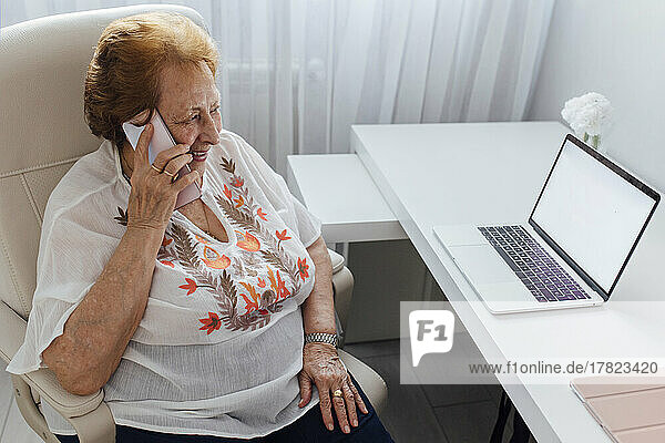 Glückliche Frau  die zu Hause mit dem Smartphone spricht