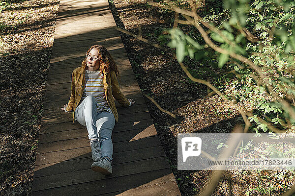 Young woman sitting on footpath in forest