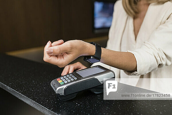 Hand einer Geschäftsfrau  die im Restaurant kontaktlos mit einer Smartwatch bezahlt