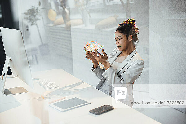 Young businesswoman examining architectural model at office