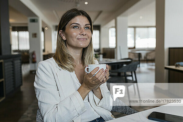 Smiling businesswoman holding coffee cup at restaurant