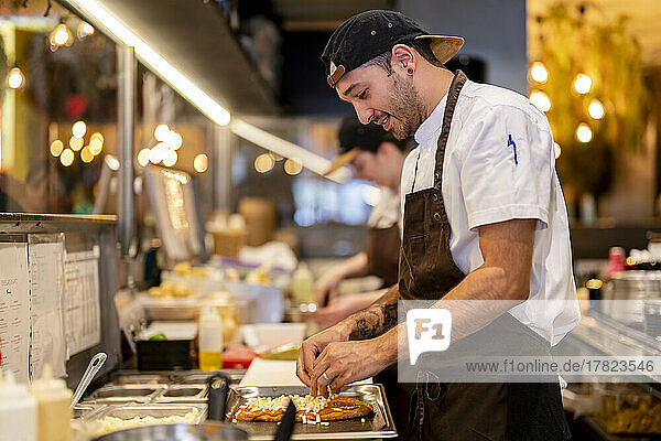 Smiling man preparing food at restaurant kitchen