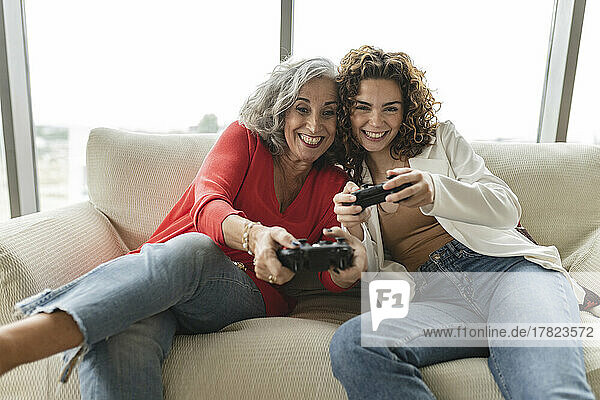 Happy senior woman with friend playing video games