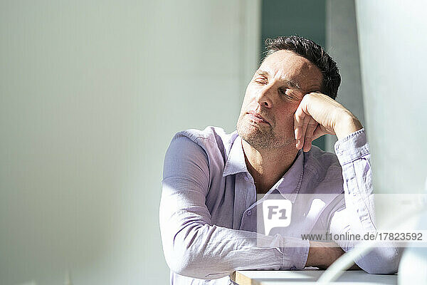 Mature businessman taking nap at desk in office