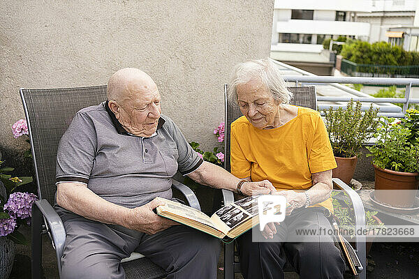 Älterer Mann und Frau betrachten Fotoalbum auf Balkon