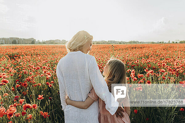 Smiling woman talking with daughter in poppy field