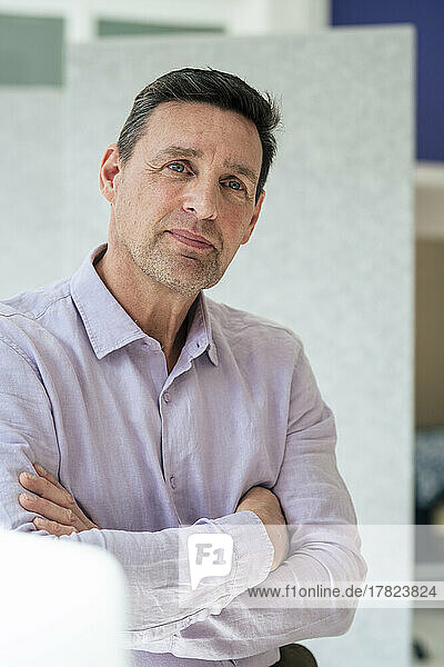 Businessman with arms crossed looking away at office