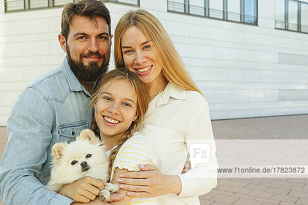 Happy family with dog standing in front of building