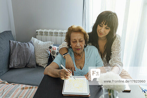 Smiling woman with grandmother using tablet PC at home