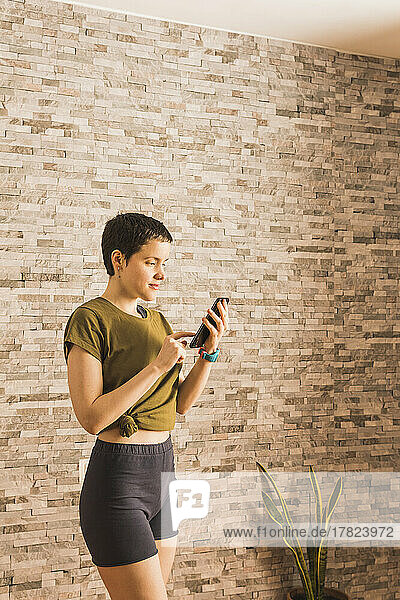 Woman using smart phone in front of wall