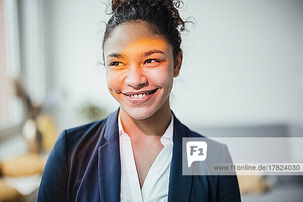 Smiling young businesswoman standing in office