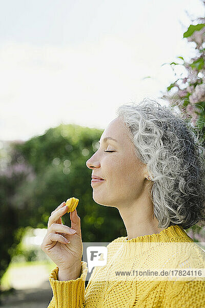 Happy woman eating macaroon at park