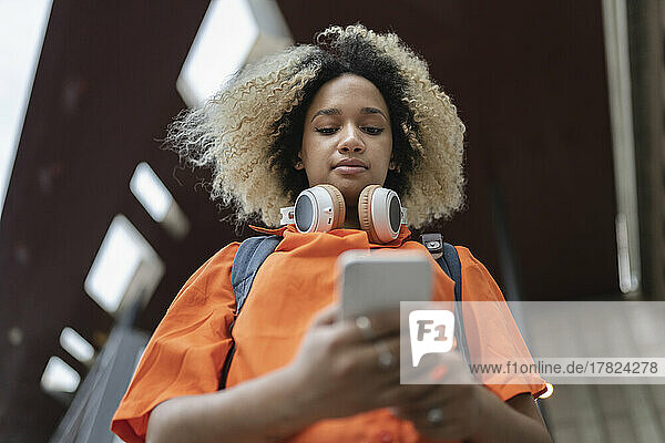 Woman with headphones using mobile phone
