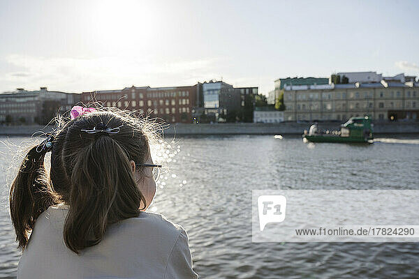 Girl with pigtails looking at river