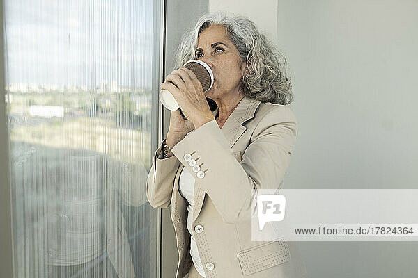 Businesswoman drinking coffee from disposable cup at office