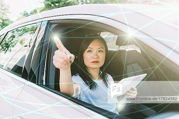 Businesswoman with tablet PC connecting lines and dots on virtual screen in car