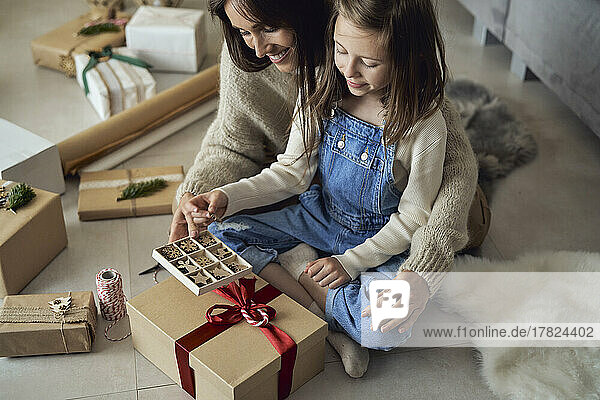 Smiling girl and mother with decoration box packing gift at home