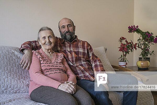 Happy senior woman with mature man sitting on sofa at home