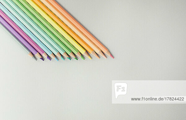 Studio shot of row of colored pencils lying against white background