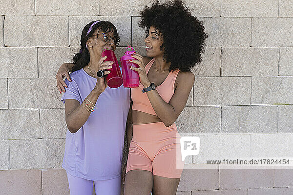 Mother and daughter with water bottles in front of wall