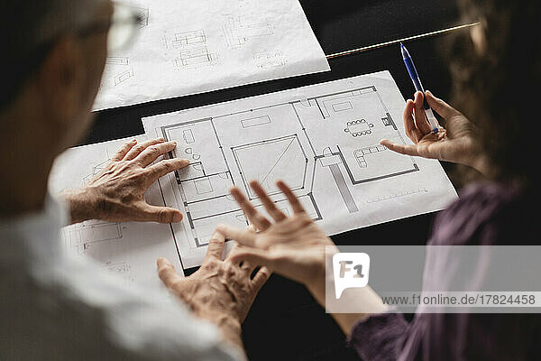 Business colleagues discussing over floor plan on table at office