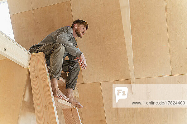 Mann sitzt auf der Leiter im zweiten Stock eines Öko-Hauses
