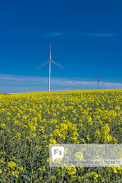 Wind turbine at field on sunny day
