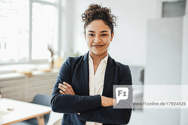 Smiling businesswoman with arms crossed standing in office