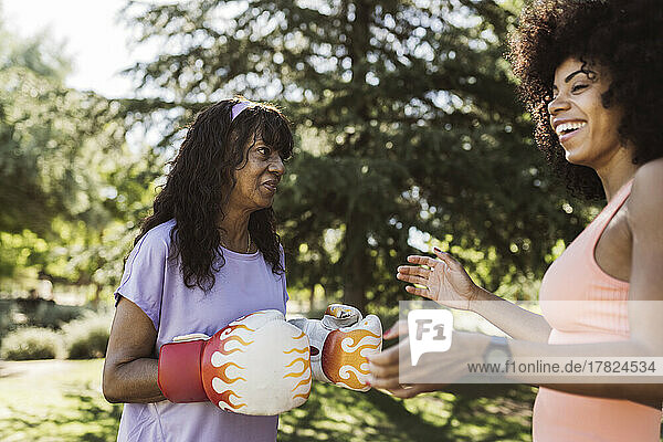 Frau lacht mit Mutter mit Boxhandschuhen im Park