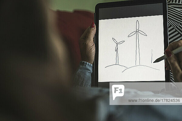 Freelancer making sketch of wind turbines on graphics tablet at home office
