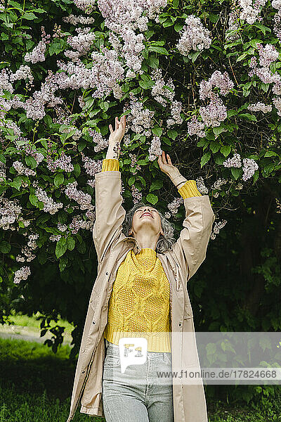 Frau berührt Blumen  die unter Blumen im Park stehen