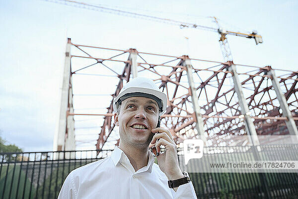 Happy engineer talking on smart phone at construction industry